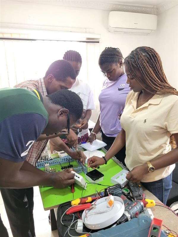 Students crowded around an electrical wiring and control rig
