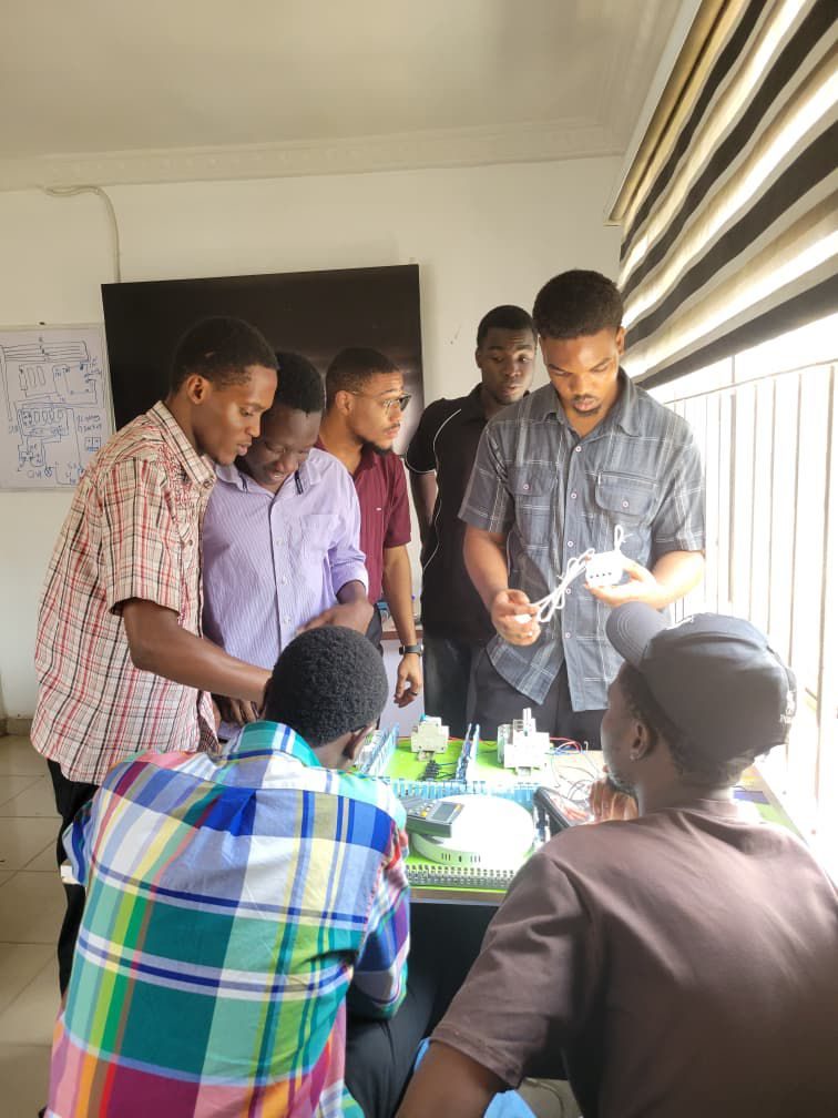 Group of students examining a PLC control trainer board