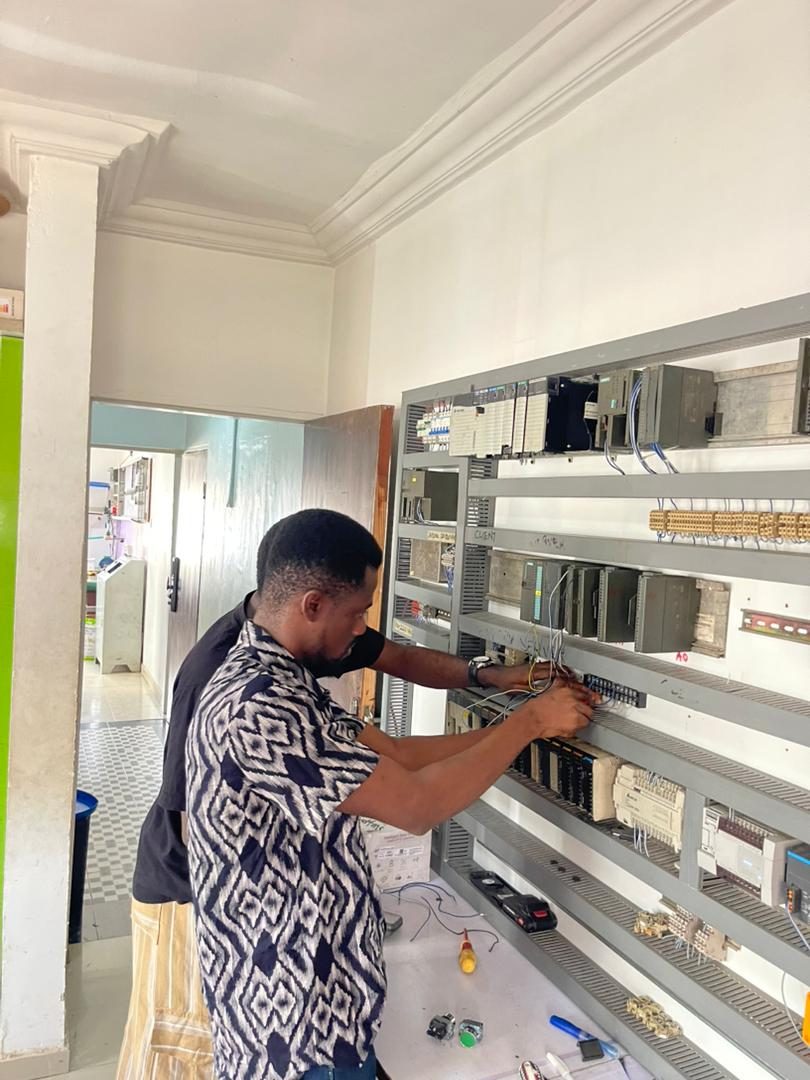 Technician wiring a Siemens PLC panel rack